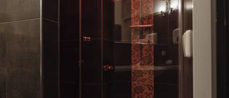 A modern shower with a glass enclosure, a red-tiled floor, and a visible showerhead.