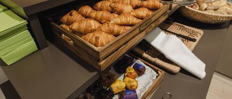 A breakfast buffet with various pastries, a coffee machine, and utensils.