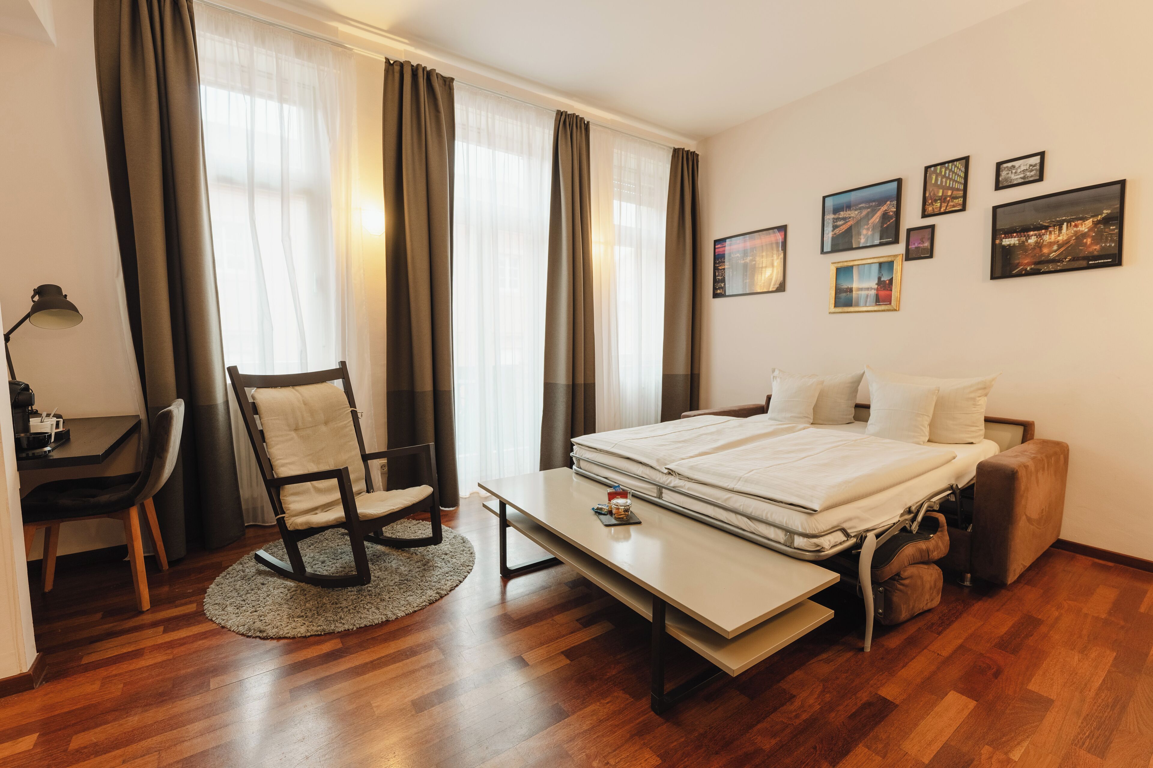 Una habitación de hotel con cama, escritorio, silla y una mesita.
