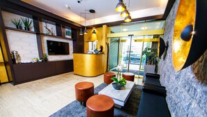 Un área de recepción moderna con mostrador, asientos y una pantalla grande.