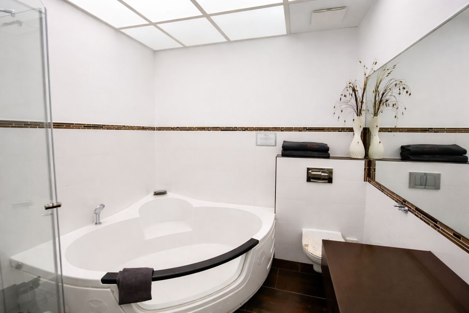 A modern bathroom with a glass-enclosed shower, a freestanding bathtub, and a vanity with a mirror.
