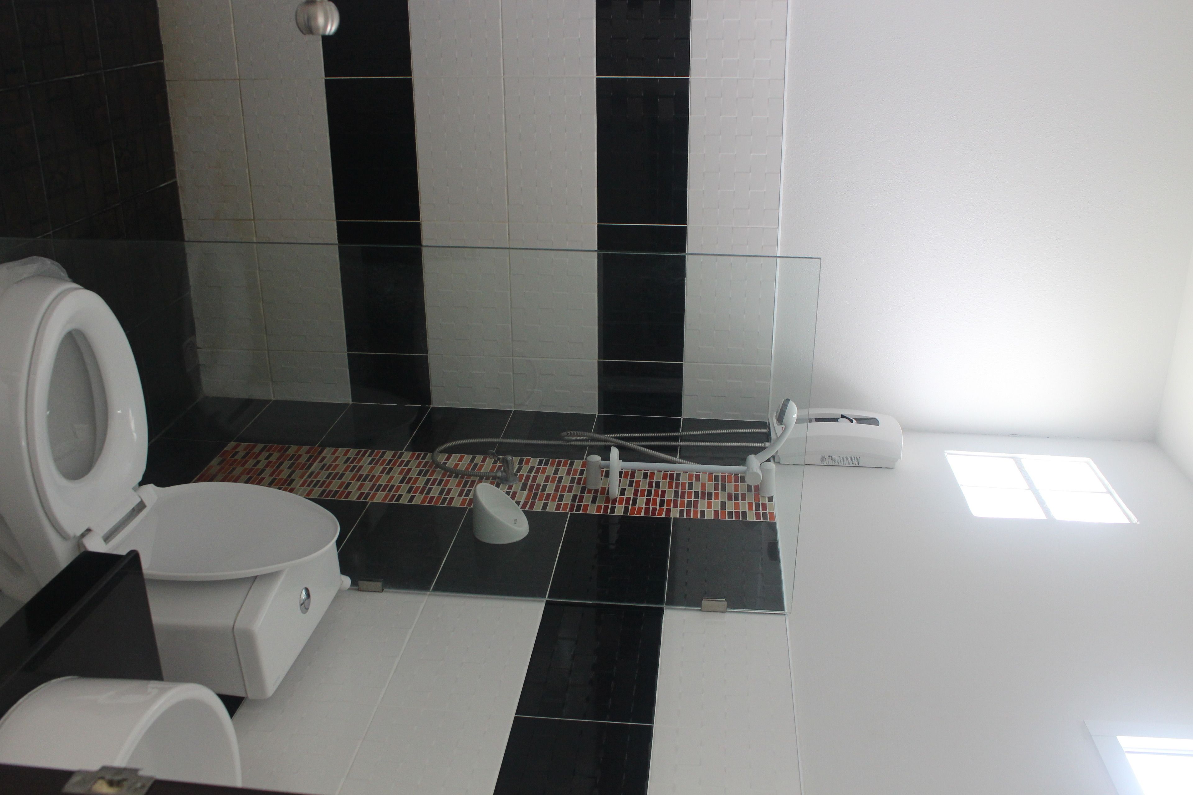 Une salle de bain avec des toilettes, une douche et un sol carrelé.