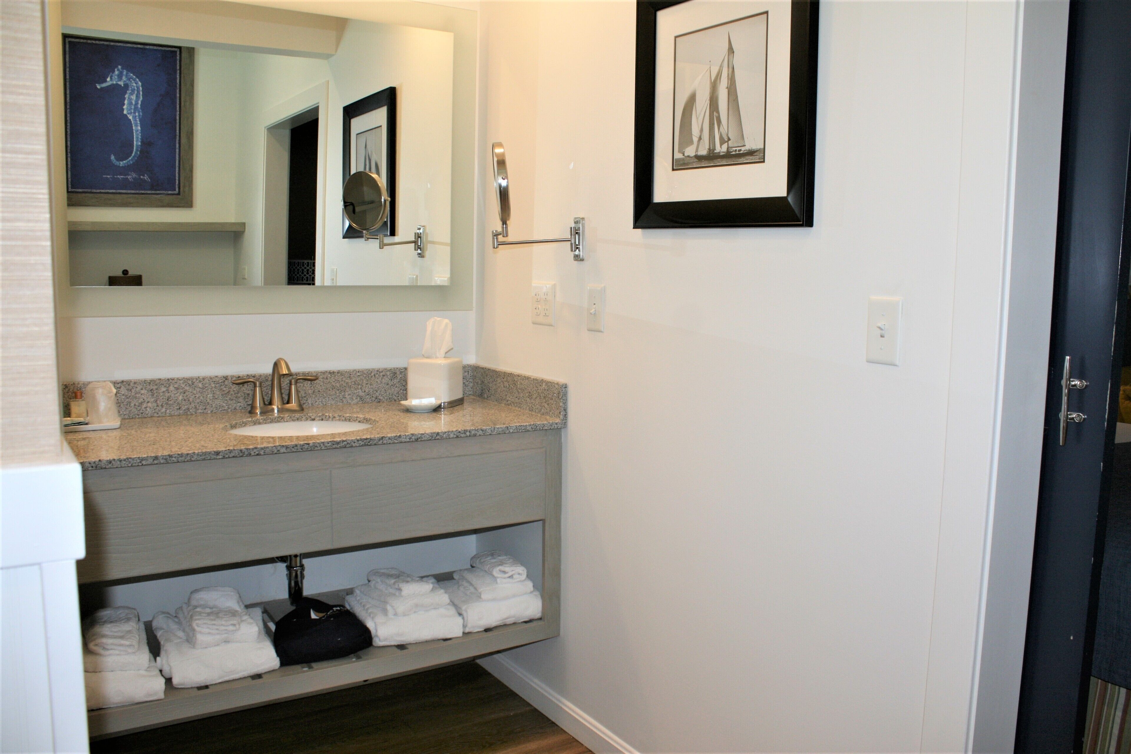 A bathroom with a sink, mirror, towel rack, and a framed picture on the wall.