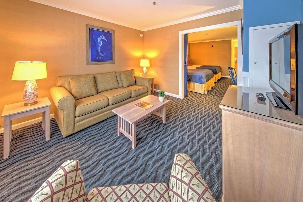 A hotel room with a sofa, a small table, a TV, and a bed.
