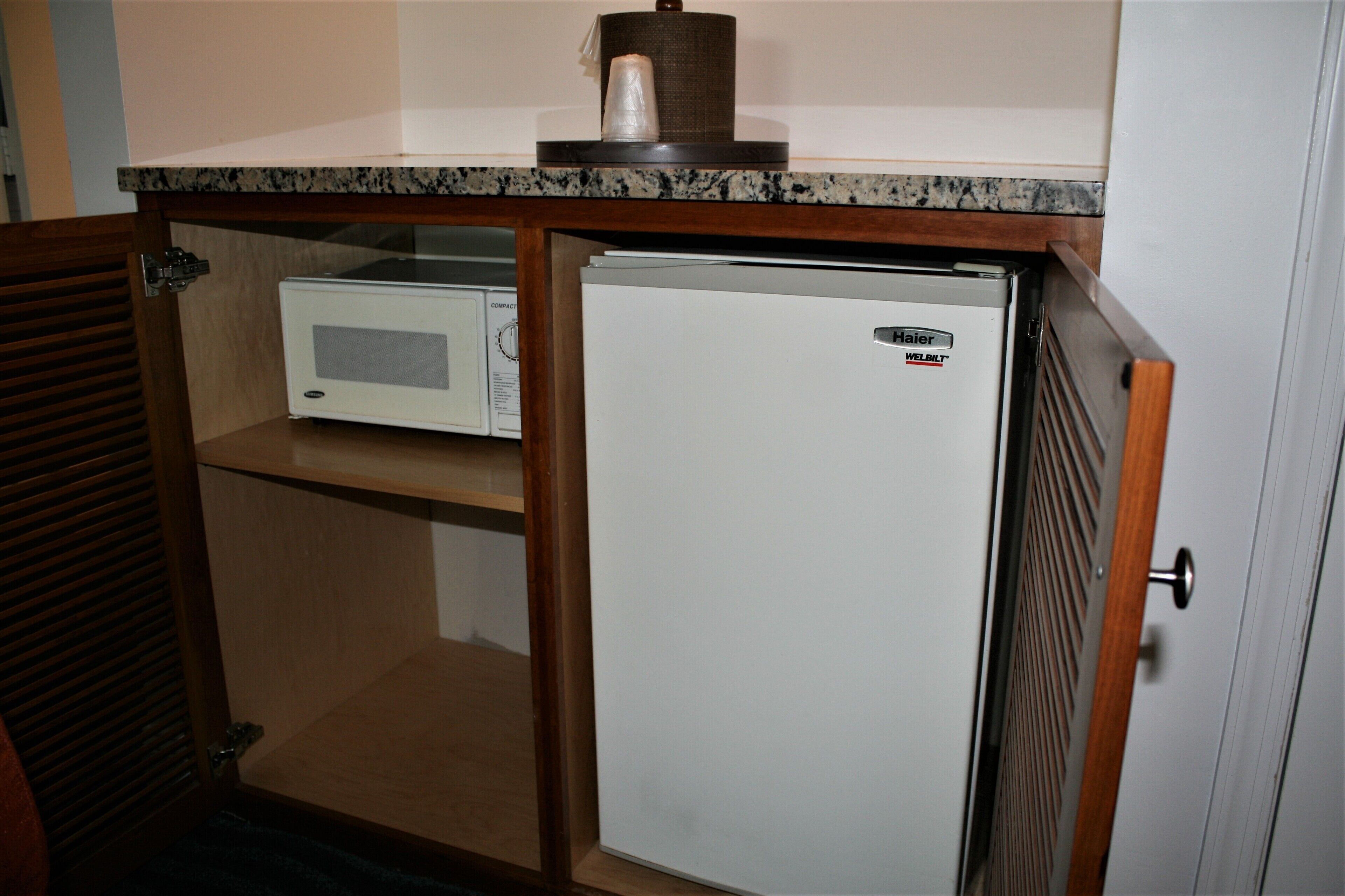 A compact kitchen with a built-in microwave and a small refrigerator.