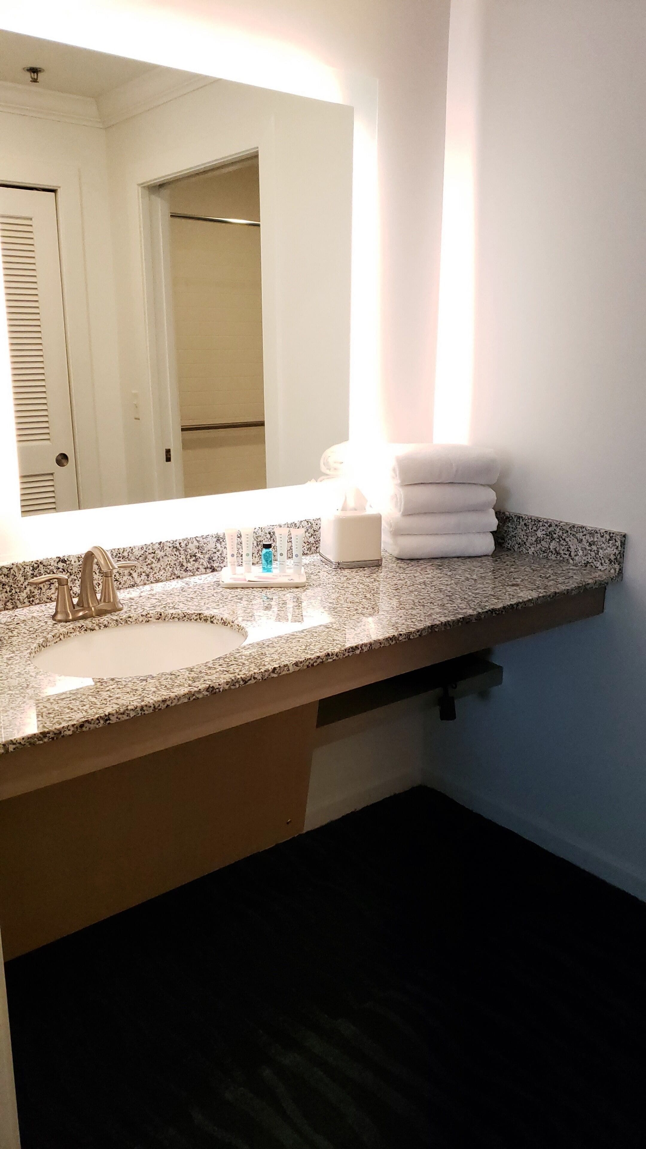 A bathroom with a granite countertop, a sink, a mirror, and a towel rack.