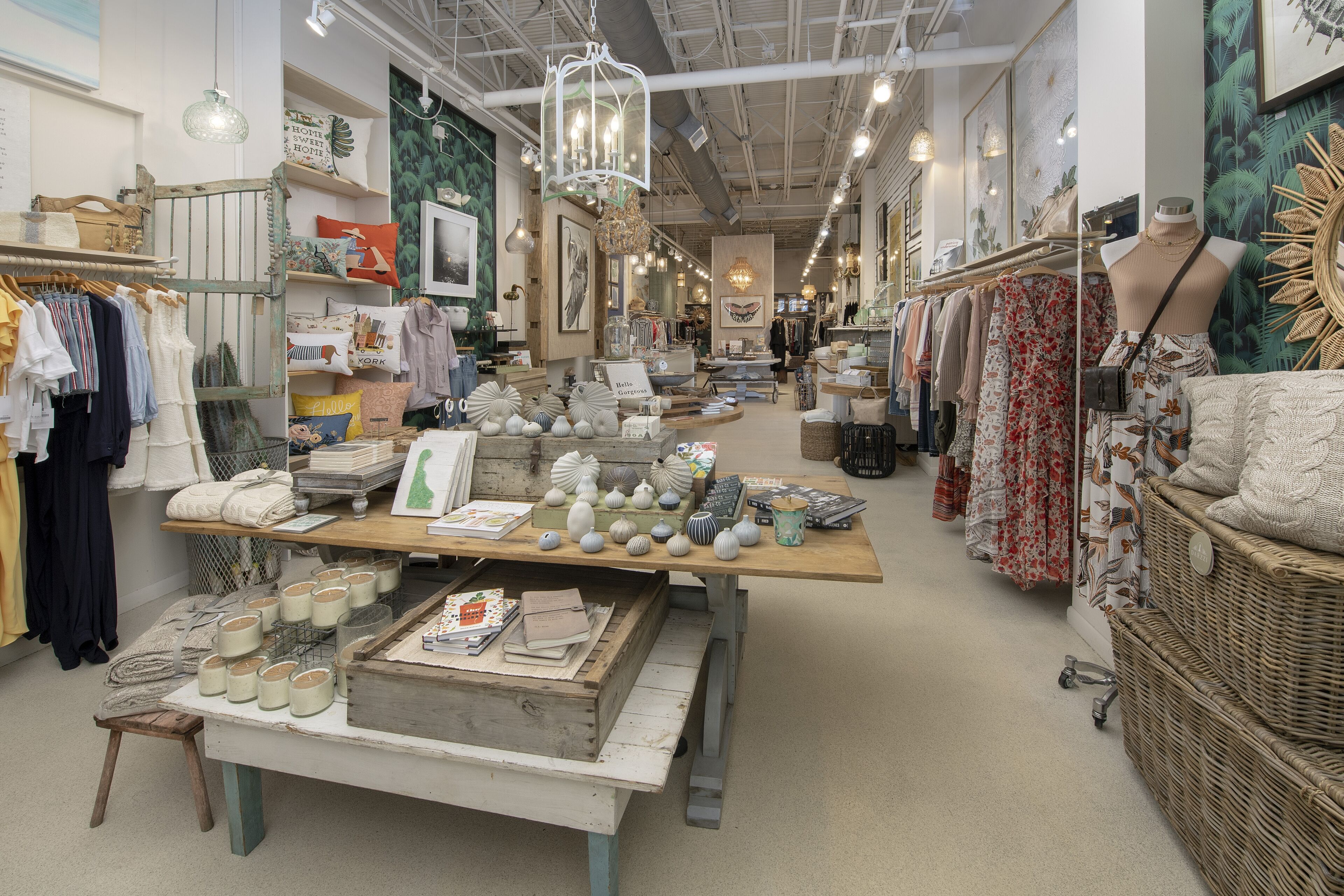 A boutique store with shelves of clothing, a display table with decorative items, and a mannequin.