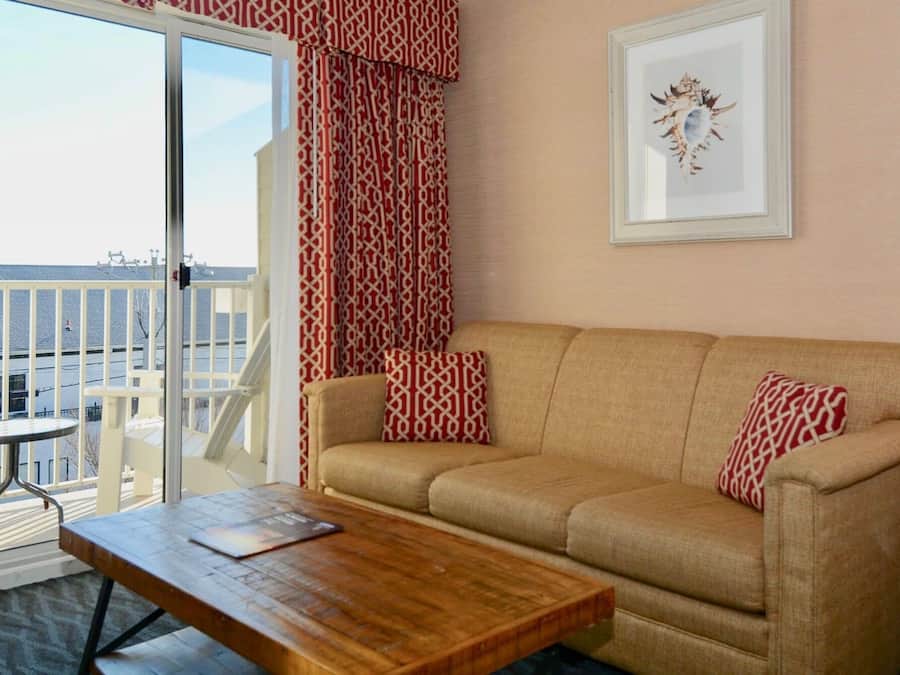 Ett mysigt rum med en beige soffa, ett träbord och ett inramat konstverk på väggen.