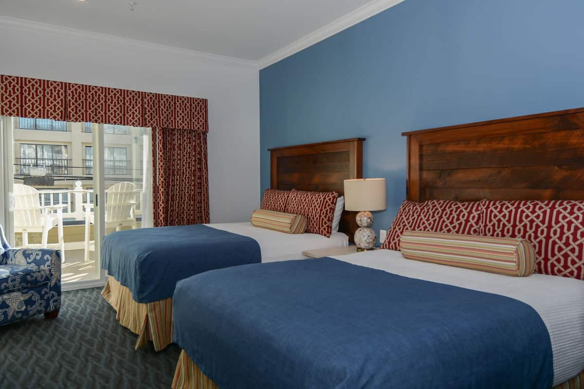 A hotel room with two beds, a large window, and a balcony.