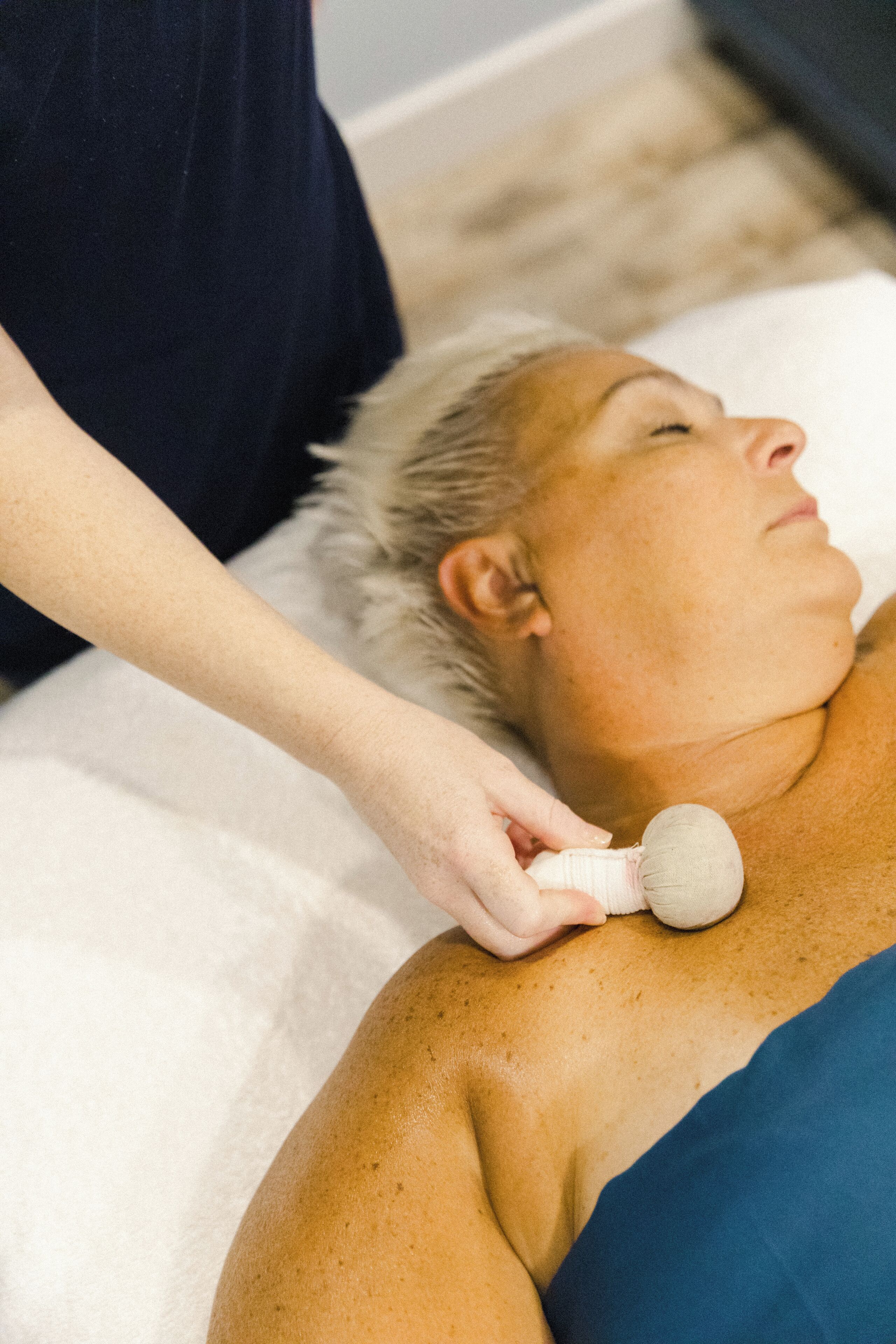 Eine Person liegt auf einer Massageliege und erhält eine Nackenmassage.