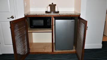 A compact kitchen with a microwave and refrigerator, wooden cabinets, and a countertop.