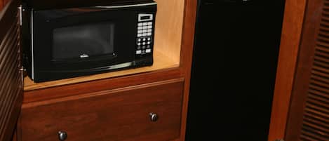 Un microondas y un refrigerador dentro de un mueble de madera.