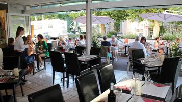 An outdoor dining area with tables and chairs, umbrellas, and a view of the street.