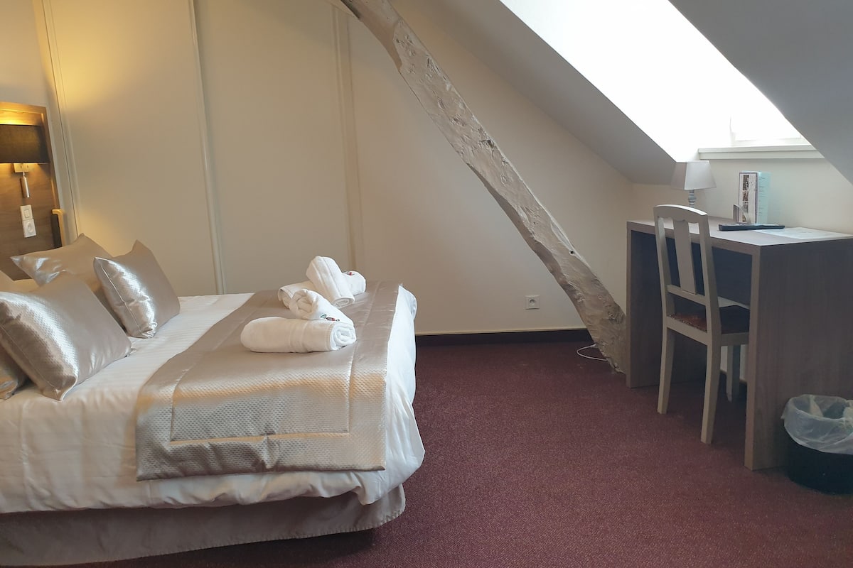 Ein Hotelzimmer mit Bett, Kissen, Schreibtisch und Stuhl.