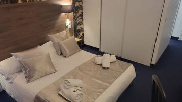A hotel room with a bed, pillows, a bedside lamp, a wardrobe, and a chair.