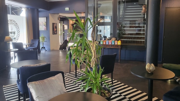 A modern lobby with a checkered floor, seating areas, a staircase, and a reception desk.