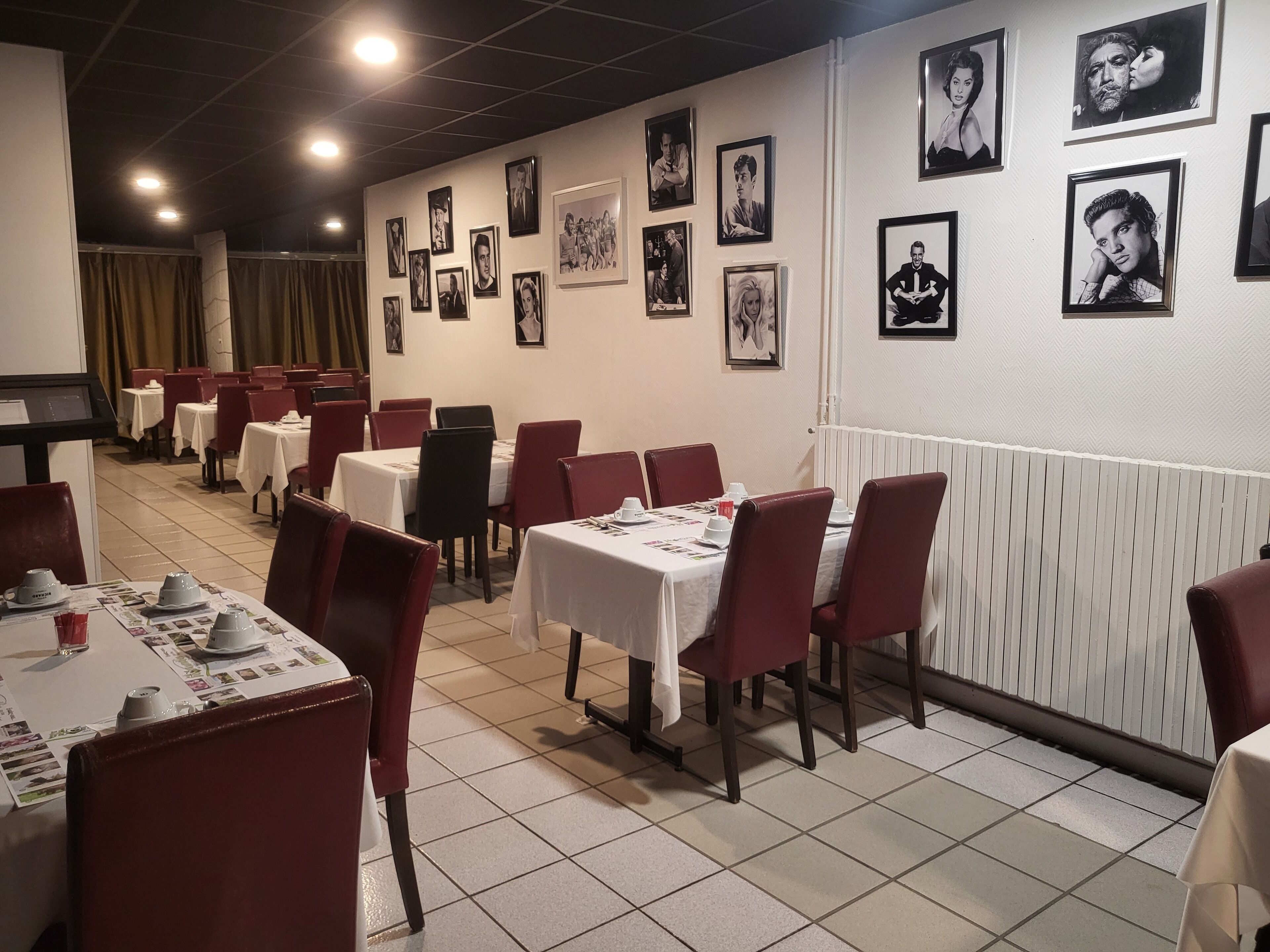 Un ristorante con diversi tavoli e sedie, alcuni con menù e bicchieri sopra.