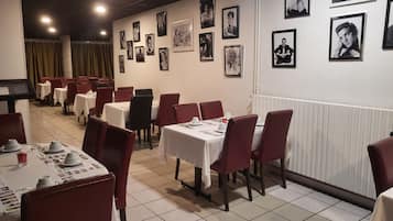 Un ristorante con diversi tavoli e sedie, alcuni con menù e bicchieri sopra.