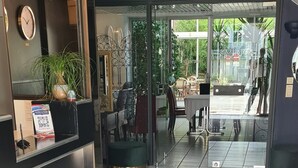 A hotel reception area with a dark carpet leading to a glass door entrance.
