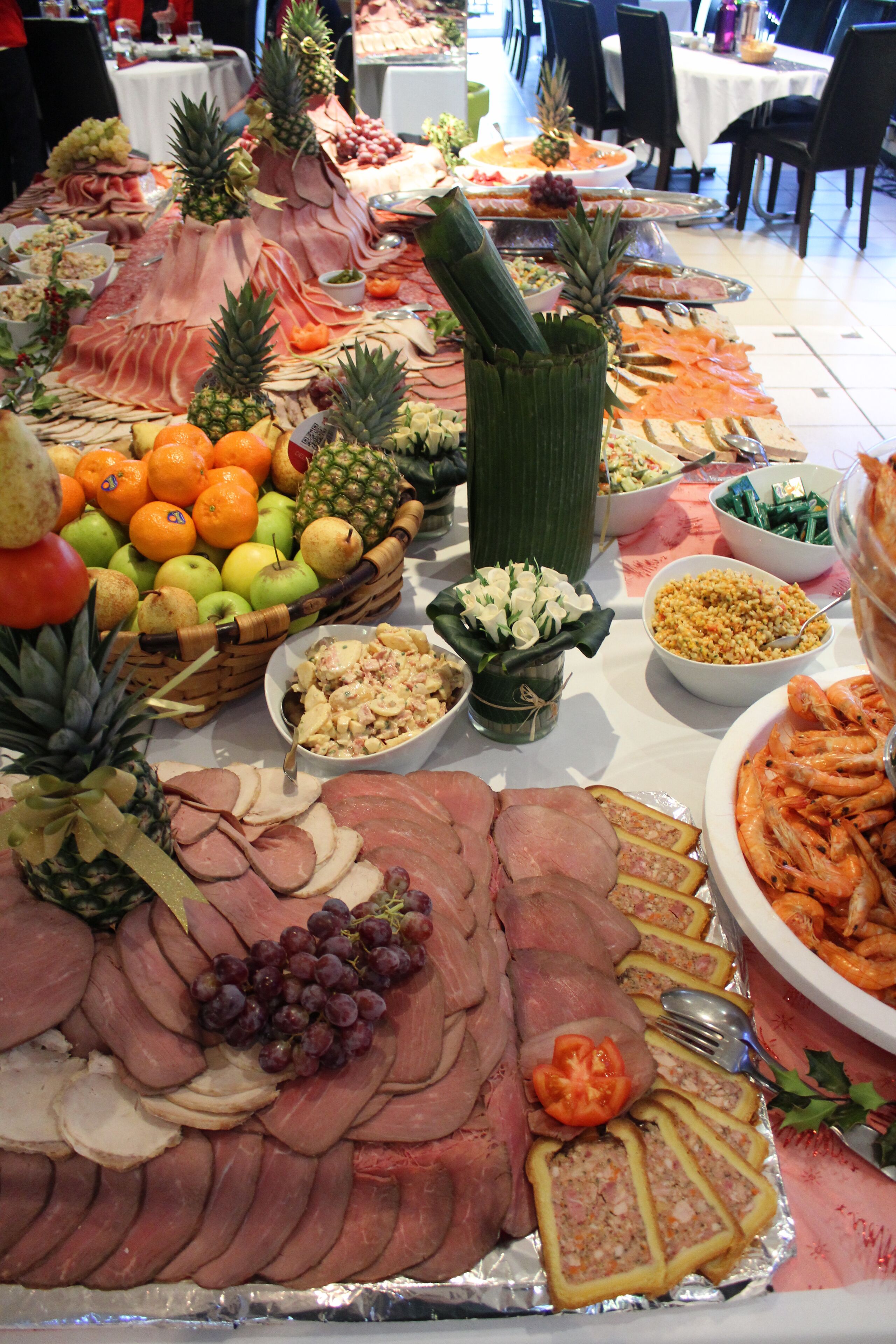 A buffet table with various food items including meats, fruits, and vegetables.