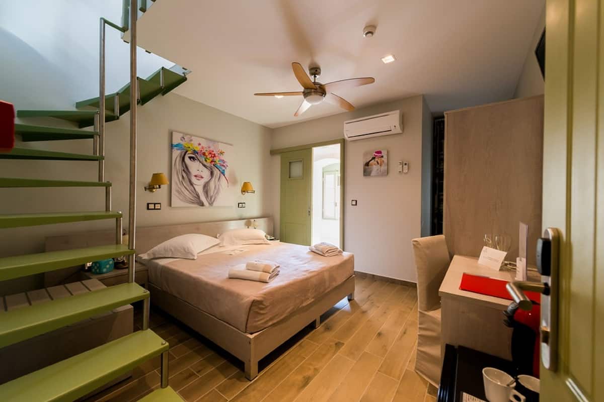 Quarto moderno com cama, escrivaninha, cadeira, escada e ventilador de teto.