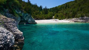 Eine Küstenlandschaft mit klarem türkisblauem Wasser, felsigen Klippen und einem Sandstrand.