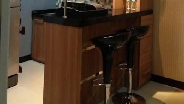 Una cocina moderna con armarios de madera, encimera negra y una barra con taburetes.