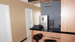 Una cocina moderna con encimera negra, armarios de madera, refrigerador de acero inoxidable y pileta negra.