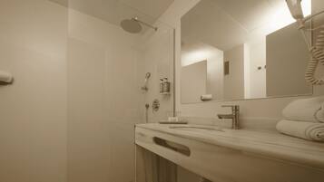 Un baño moderno con ducha, lavamanos y secador de pelo.