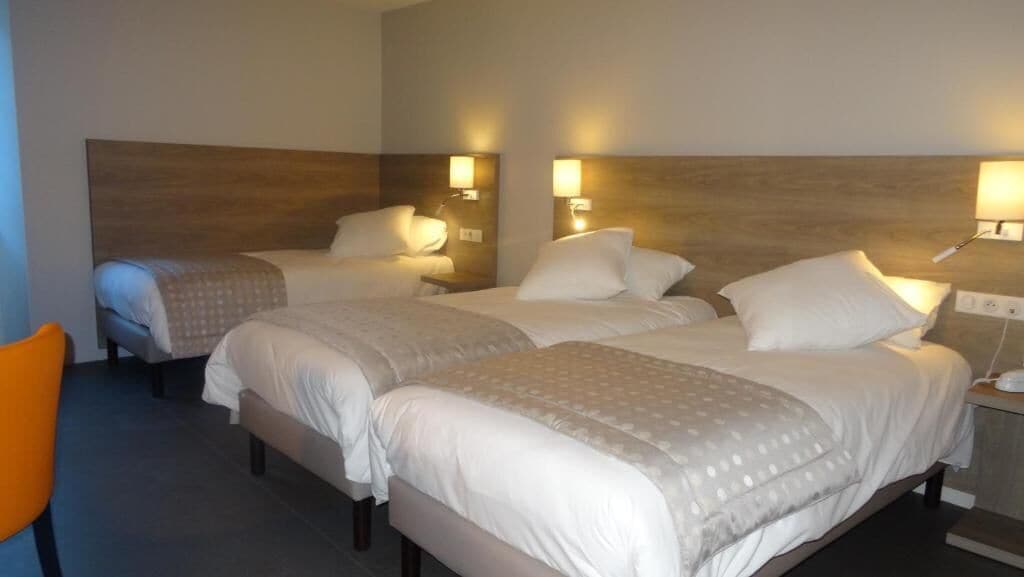 Habitació d'hotel amb dos llits, cadascun amb un capçal de fusta i petites làmpades laterals.