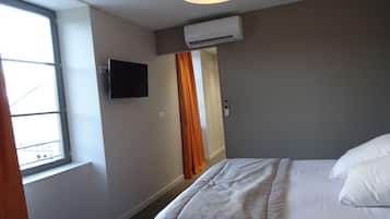 Habitación de hotel con cama, televisión montada en la pared, aire acondicionado y ventana con cortinas.