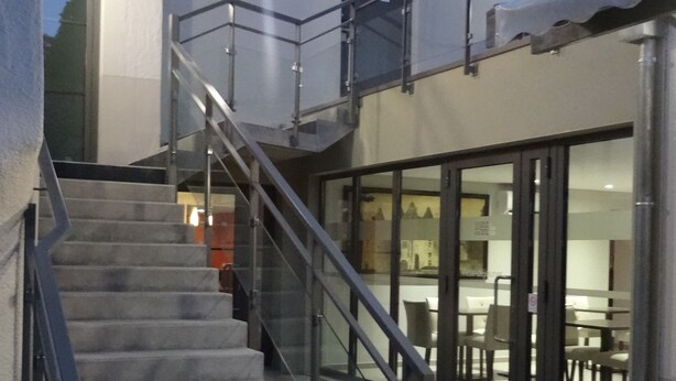 Una escalera que conduce a un edificio con entrada por una puerta de vidrio.