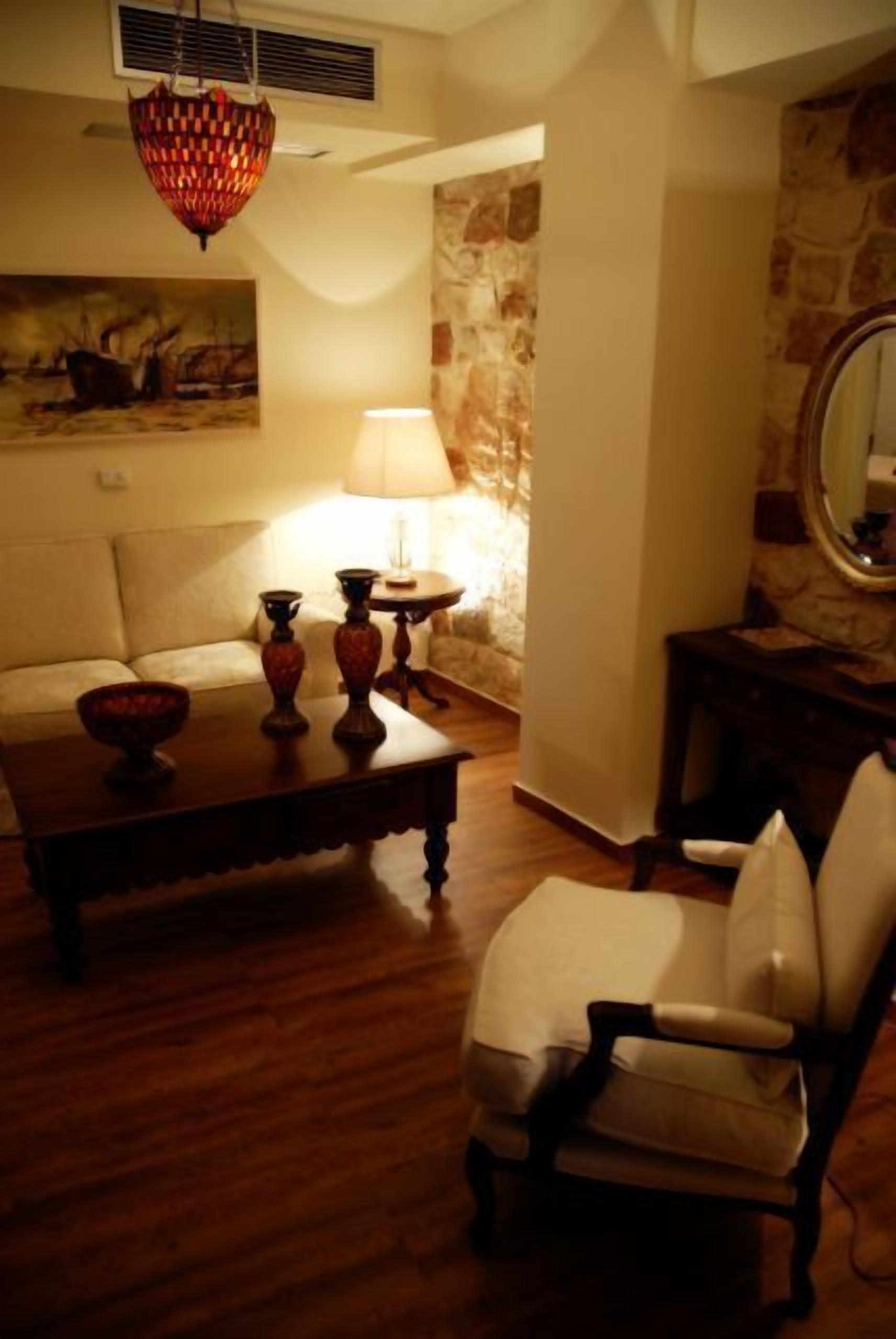Una sala de estar con un sofá, una mesa de centro con objetos decorativos, una lámpara y una silla.