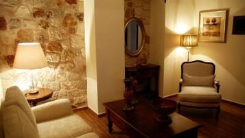 Una sala de estar acogedora con una pared de piedra, un espejo redondo, una mesa de centro de madera, un sillón color beige y una lámpara.
