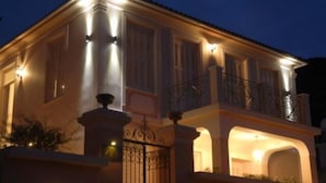 A two-story building with a balcony on the upper floor, a gated entrance, and a well-lit facade. - Korina Gallery Hotel (Ithaki)