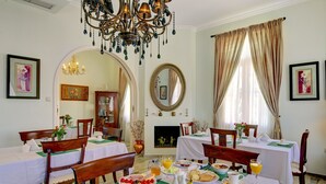 A dining area with tables set for breakfast, including plates of fruit, pastries, and beverages. - Korina Gallery Hotel (Ithaki)