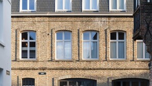 A two-story building with a brick facade, multiple windows, and a cobblestone courtyard. - B&B Zakske 13 (Bruges)