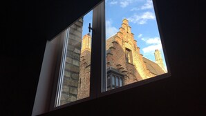 A window with a view of a brick building with a tower and a door. - B&B Zakske 13 (Bruges)