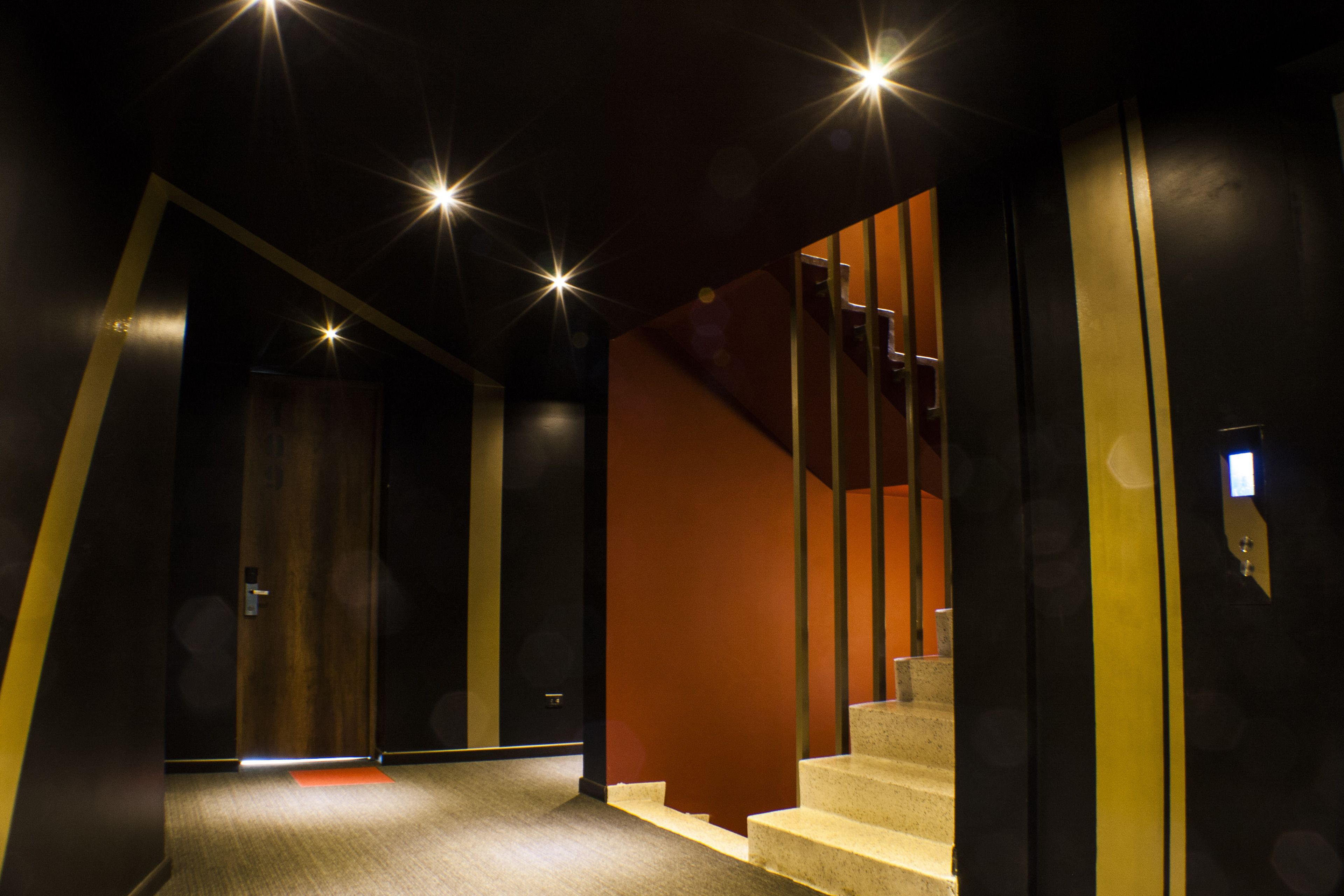 A modern interior with a staircase, carpeted flooring, and a door leading to another room.