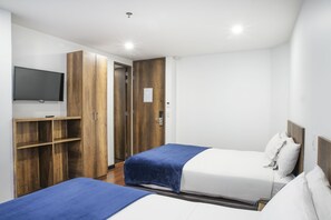 Habitación de hotel con dos camas, un televisor, armario de madera y una puerta que da a otra habitación.