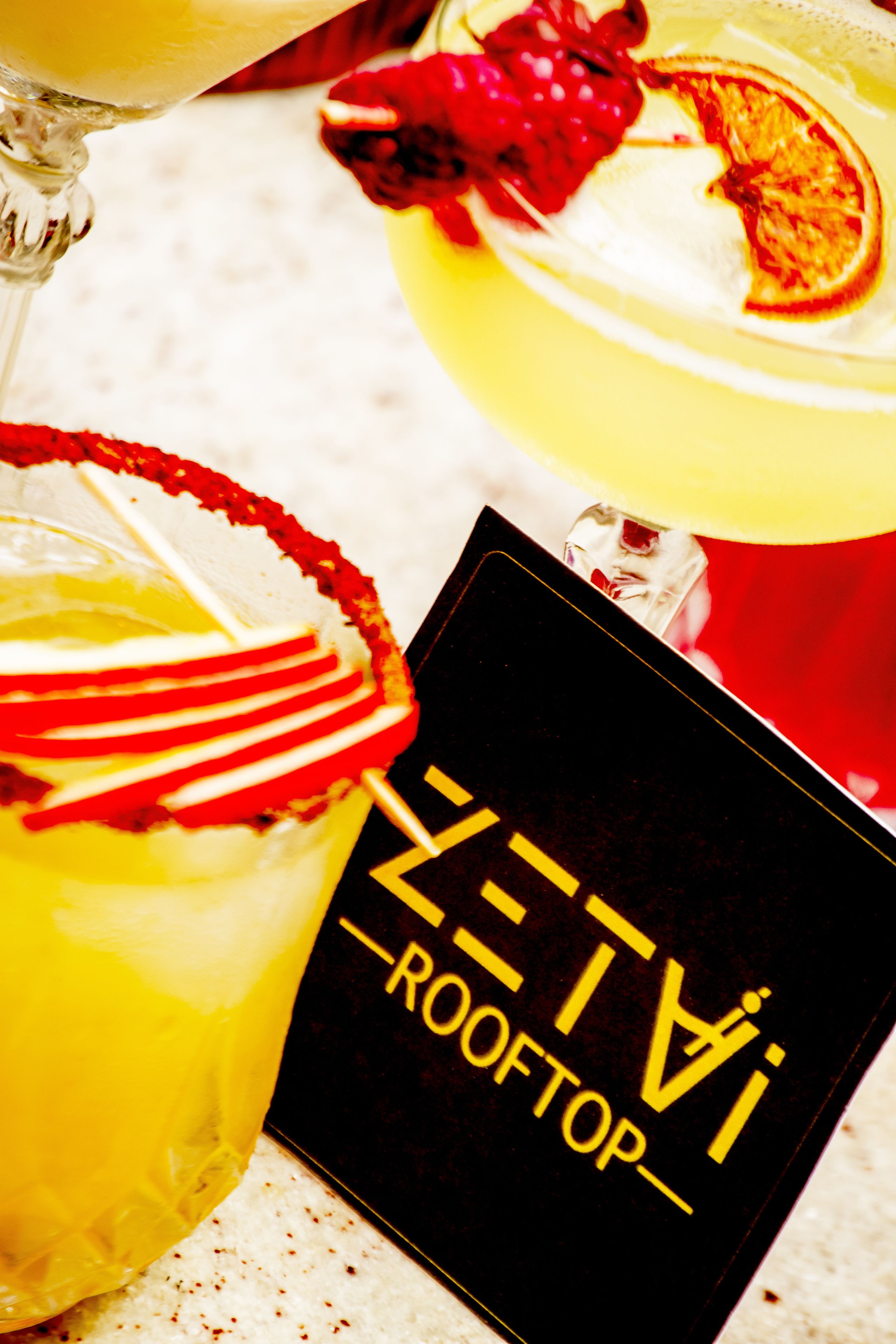 Cocktail-drinkki, jossa on limenviipale koristeena ja musta aluslasi, jossa on tekstiä.