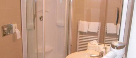 A bathroom with a glass-enclosed shower, a toilet, and a sink with a hairdryer.