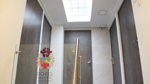 A hallway with a skylight, a glass partition, and a door with a logo. - Agora Suites Self-Service Boutique Hotel (Bogotá)