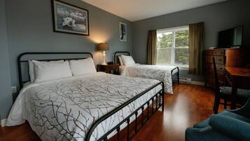 A hotel room with two beds, a desk, a chair, a television, and a window with curtains.