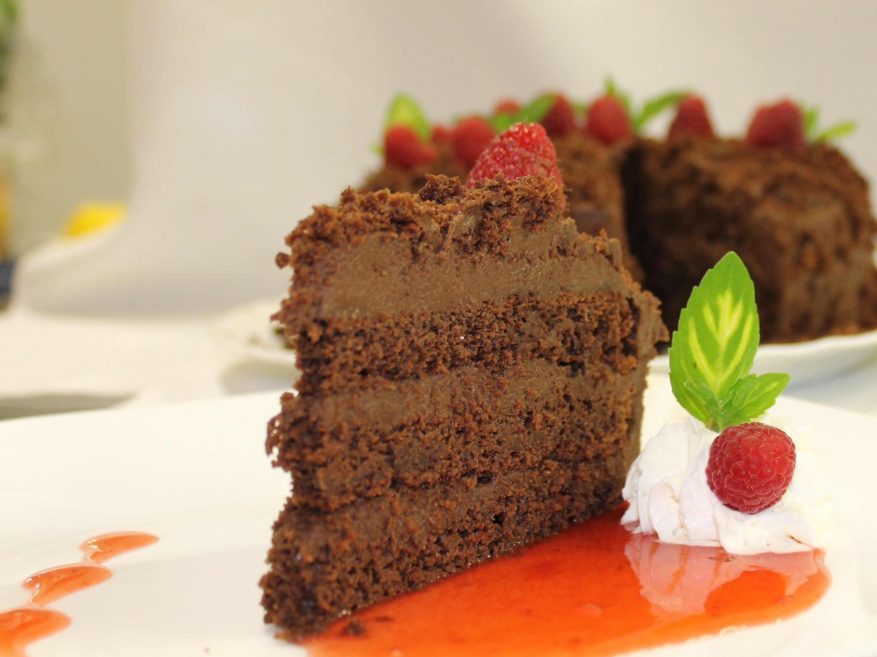 A slice of chocolate cake with strawberries and whipped cream on a plate.