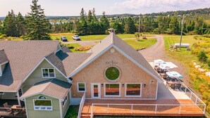 A large building with a prominent circular window and a deck area with outdoor seating. - Seawind Landing Country Inn (Charlos Cove)