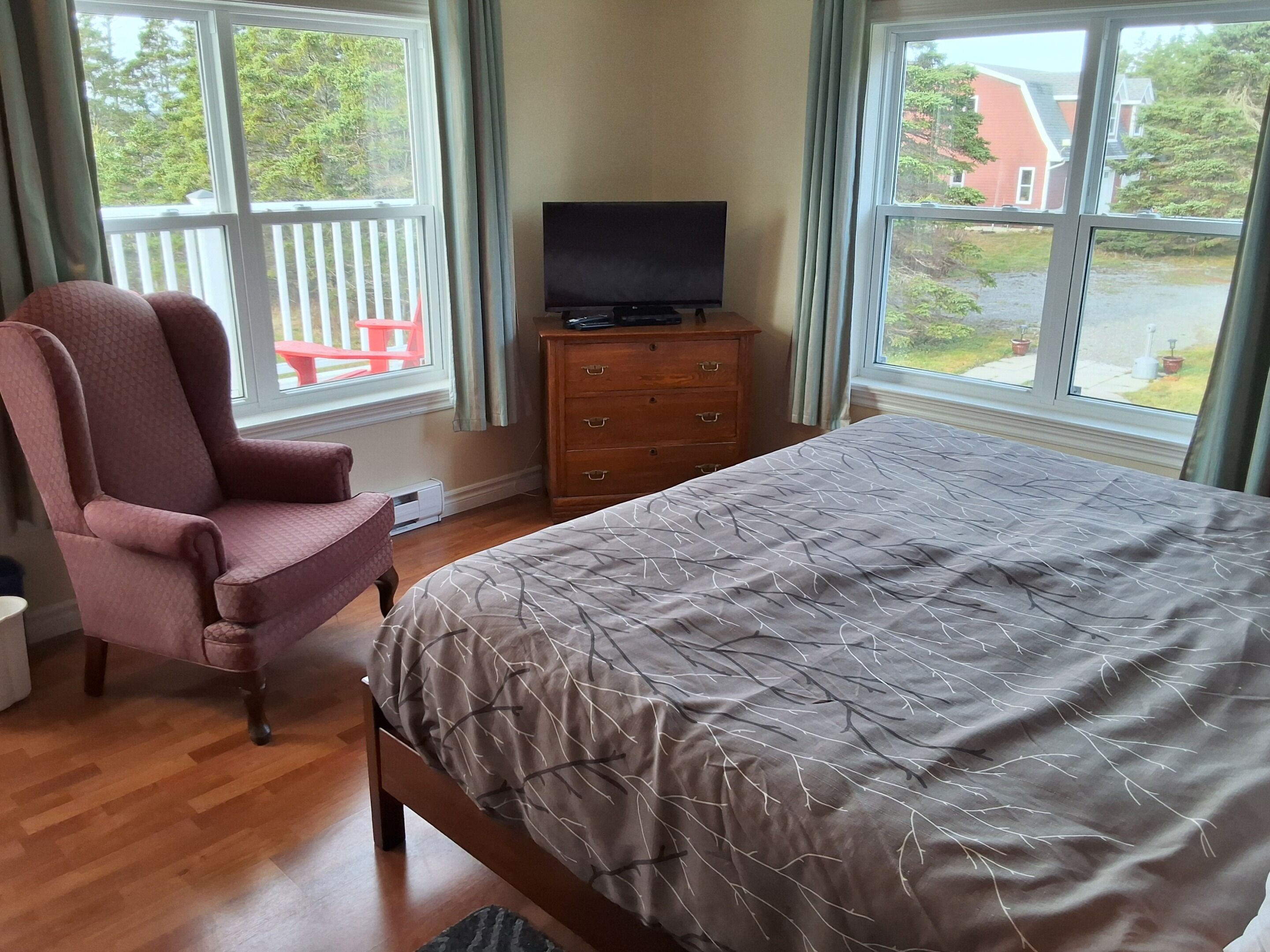 Ein Schlafzimmer mit einem Bett, einem Sessel, einem Schminktisch und einem Fernseher.