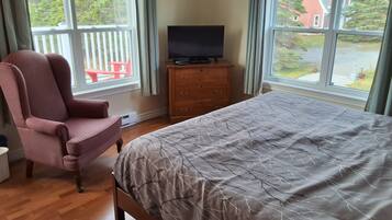 Ein Schlafzimmer mit einem Bett, einem Sessel, einem Schminktisch und einem Fernseher.