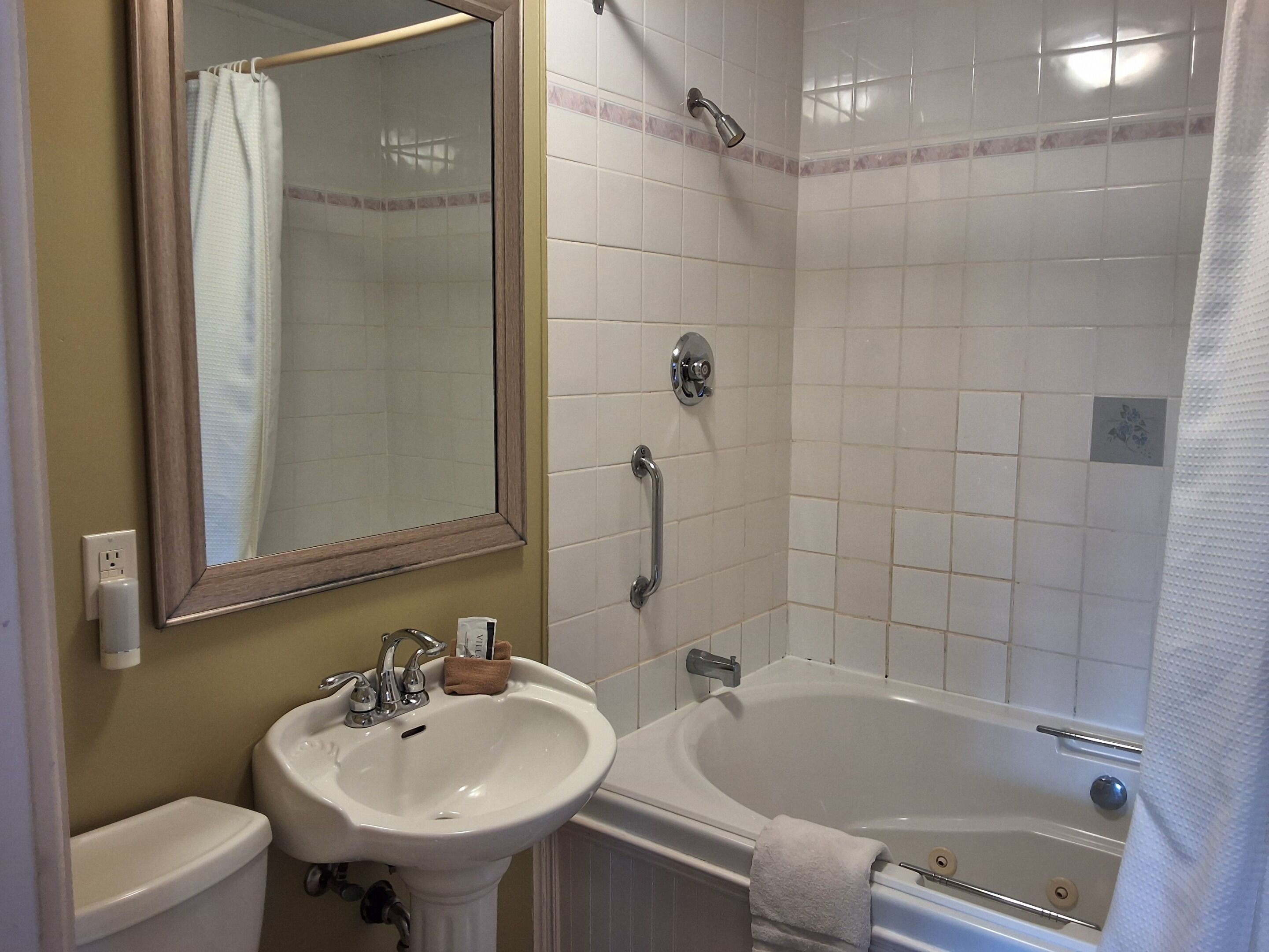 A bathroom with a sink, mirror, toilet, and bathtub.