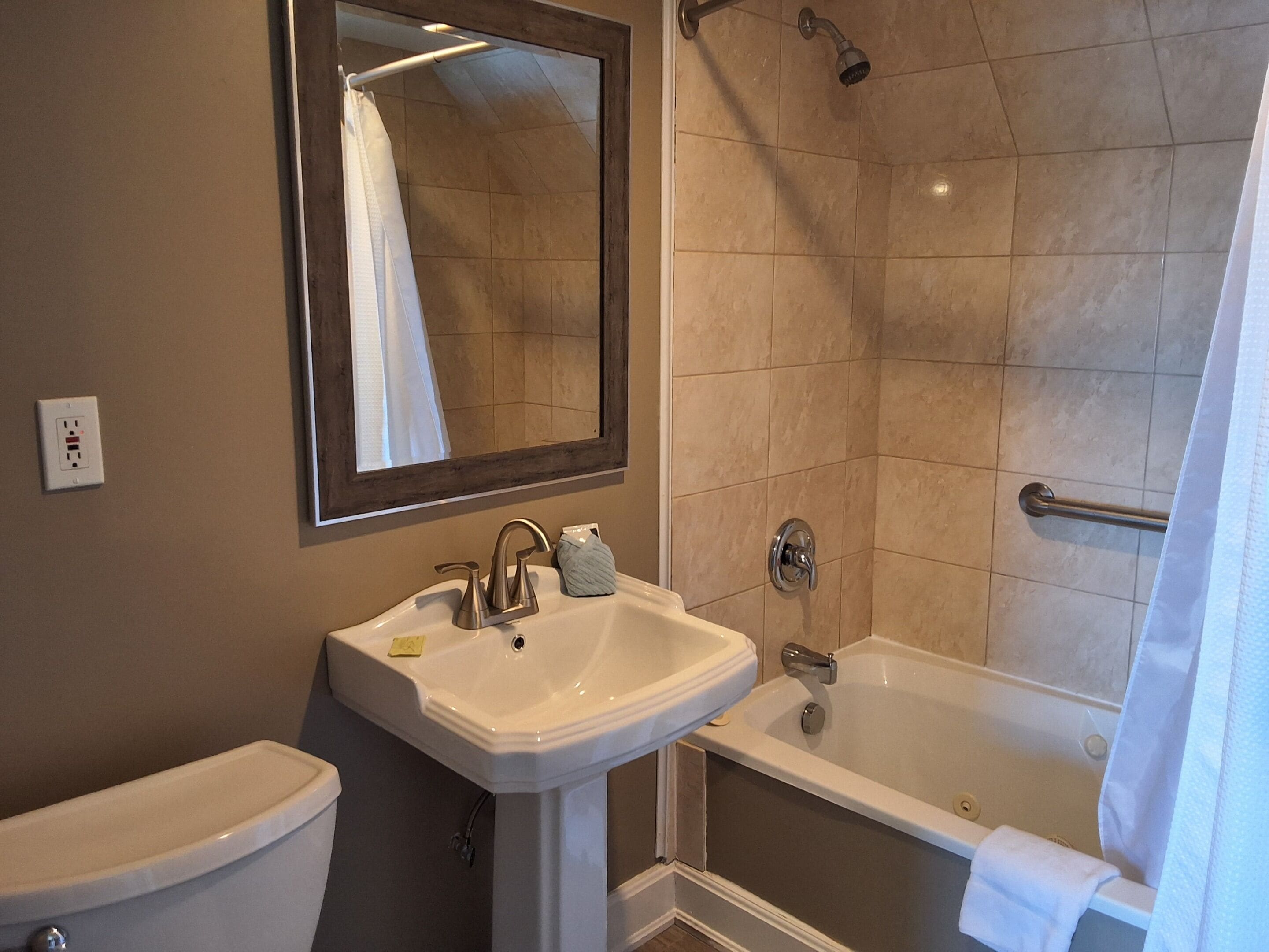 A bathroom with a sink, mirror, toilet, and bathtub.